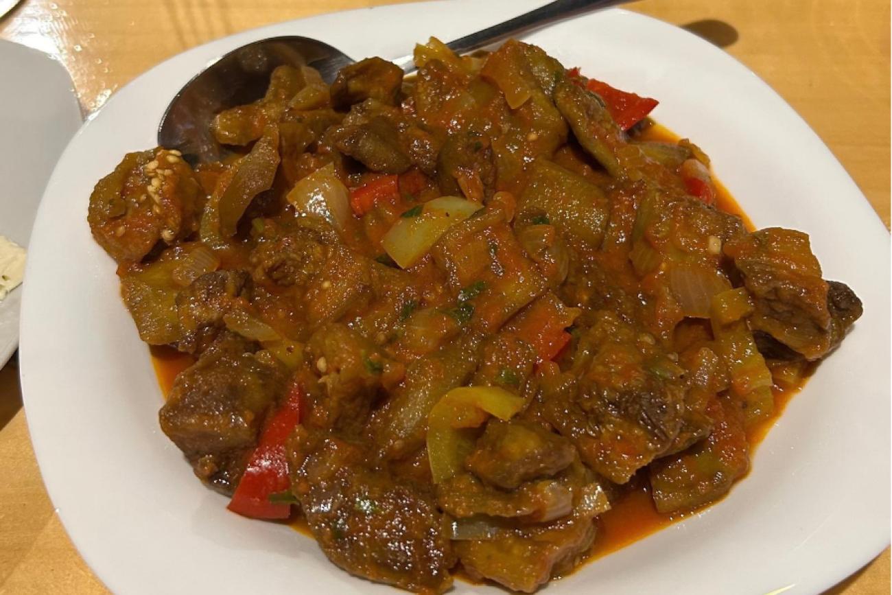 A generous serving of ajapsandali on a large white plate accompanied by a spoon